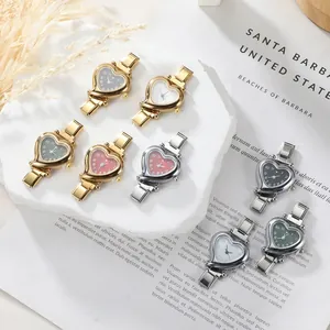 Macro shot of stylish heart-shaped finger watches with colorful dials on a white tray