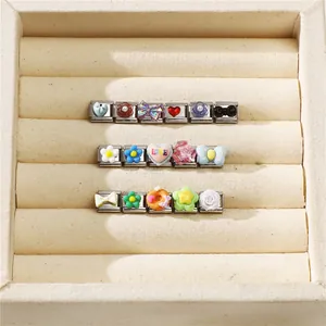 Macro view of modular Italian style stainless steel charms with floral and love motifs