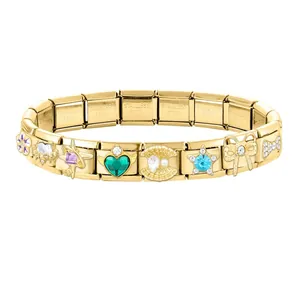 Detail of modular gold charms with green heart and star patterns on stainless steel bracelet