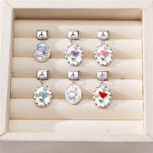 Macro view of modular Italian charms with enamel floral patterns and rhinestone inlays