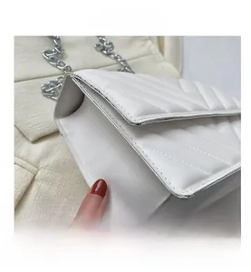 Close-up of white quilted PU leather bag with silver chain and V-shaped stitching