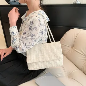 Detail of cream straw tote bag featuring fine woven texture and thick rope shoulder straps
