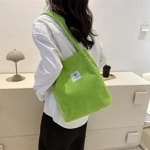 Vibrant green knitted tote bag with feather label patch shown on a shoulder strap
