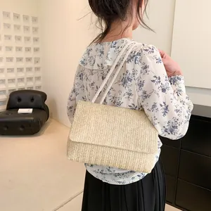 Detail showing handwoven beige straw tote bag with white rope strap on female model shoulder