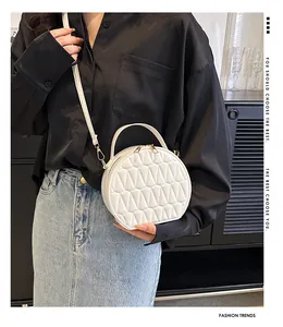 Détail d'un sac rond blanc matelassé avec finitions dorées et bandoulière amovible