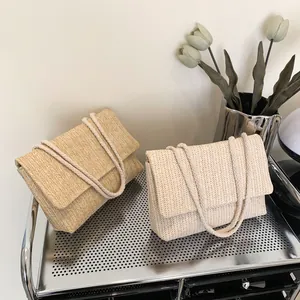 Close-up of woven straw envelope bags in beige and off-white with V-shape textures