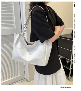 Detail of white large capacity tote bag with metal chain strap and pebble leather texture
