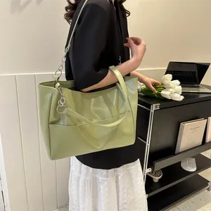 Detail of light green tote bag featuring silver chain decor and front pocket design