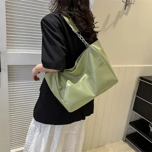Detail of light green tote bag featuring front pockets and silver chain shoulder strap