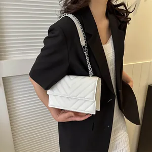White V-quilted flap shoulder bag with silver chain strap shown worn by a model