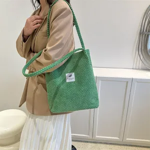 Close-up of green knit tote bag with woven texture and a white rectangular fabric label