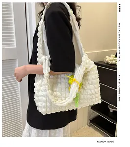White puffy bubble texture tote bag featuring a green charm shown on model in a modern room