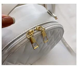 Détails de la fermeture éclair dorée et texture matelassée sur le sac blanc