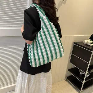 Close-up of green and white striped popcorn fabric tote bag worn on shoulder by a model