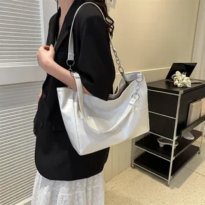 Detail of white large tote bag featuring metallic ring buckle and side pocket
