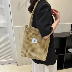 Detailed view of khaki tote bag with white leaf patch and long handle on shoulder
