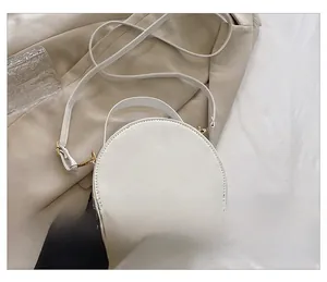 Détails de l'arrière d'un sac à bandoulière blanc demi-cercle avec finitions dorées sobres
