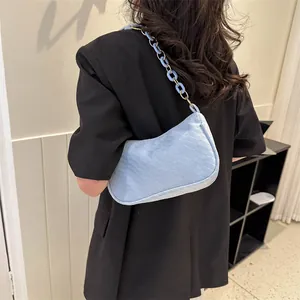 Detail showing light blue corduroy underarm bag with acrylic chain strap on model