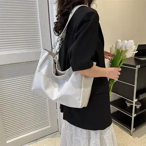 Detail of white glossy tote bag showing the side pocket and chain shoulder strap