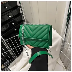 Detail of green chevron quilted crossbody bag with silver chain strap and leather pad