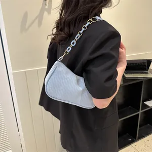 Detail of light blue shoulder bag with textured fabric and acrylic chain strap
