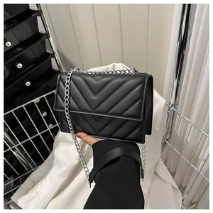 Close-up of black V-quilted texture and silver chain strap on a designer crossbody bag