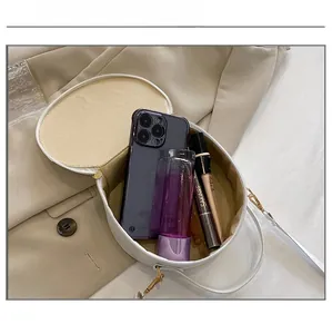 Capacité interne du sac bandoulière rond en cuir blanc montrant les essentiels