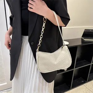 Detail of cream half-moon underarm bag with woven texture and gold chain strap