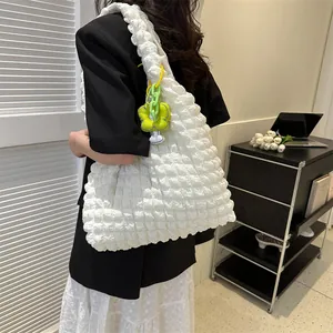 Detail of white bubble texture tote bag with a floral charm on model's shoulder