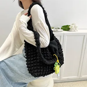 Detail of black cloud bubble textured shoulder bag with a cute green charm accessory