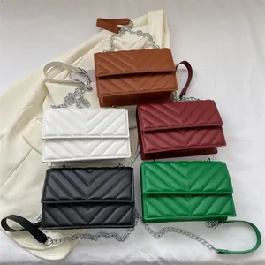 Flat lay of five color variants of V-quilted faux leather chain bags on white suit