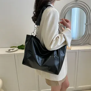 Detail view of black leather tote bag with V-shaped stitching and metal chain strap