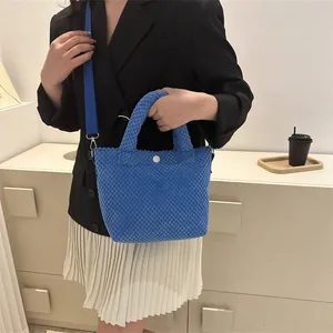 Detalle de bolso tipo cubo azul con textura de burbujas, cierre de botón blanco y correa
