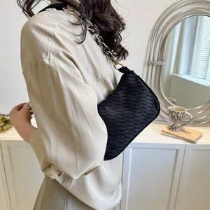 Detail of black suede hobo bag with embossed checkerboard pattern and chain strap