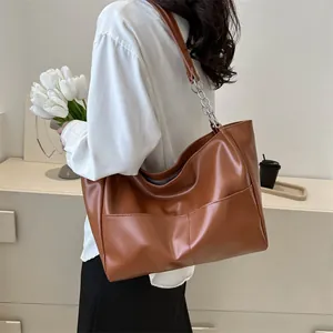 Detail of vintage caramel tote bag with dual front pockets and silver chain strap details
