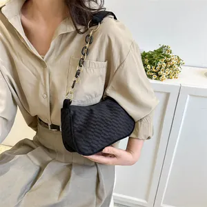 Detail of checkered texture fabric on black shoulder bag with gold chain strap