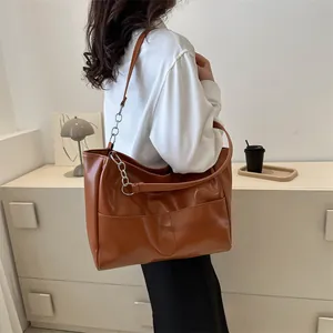 Close-up of brown faux leather tote bag with silver chain strap and side pockets