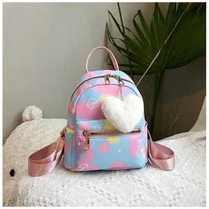 Detail of colorful tie-dye mini backpack featuring a heart print and plush heart pendant