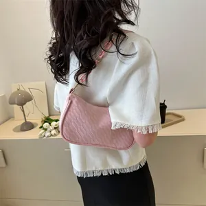 Close-up of pink woven shoulder bag with stylish plastic chain on white textured shirt