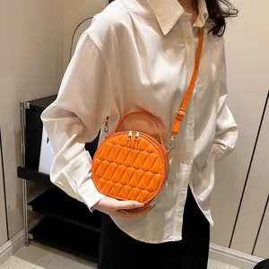 Détail du sac bandoulière rond orange avec texture plissée matelassée et fermoir doré