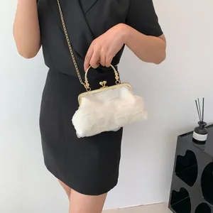 Detail of white pleated cloud bag with vintage gold metal handle and snap closure