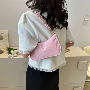 Detailed view of a pink textured baguette bag with a stylish gold-pink chain strap