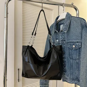 Close-up of black matte tote bag with silver chain strap and minimalist stitching