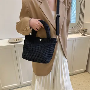 Detalle de bolso saco negro con textura, hebilla blanca y correa de nailon ajustable