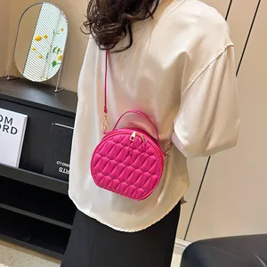 Détail d'un sac bandoulière rond rose à texture géométrique porté par un mannequin
