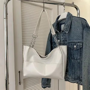 Detail of white tote bag featuring stitching pocket and silver metal chain strap
