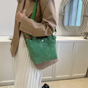 Detalle del bolso tipo saco de punto verde con textura tejida y correa de lona ancha
