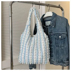 Detail of blue and white striped puffy tote bag hanging on a rack with a denim jacket