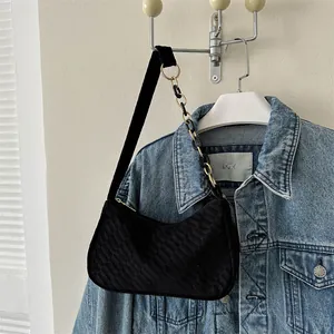Detail of black crescent shoulder bag featuring square embossed texture and chain strap