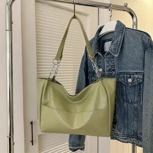Detail view of avocado green tote bag with silver chain strap on a clothing rack